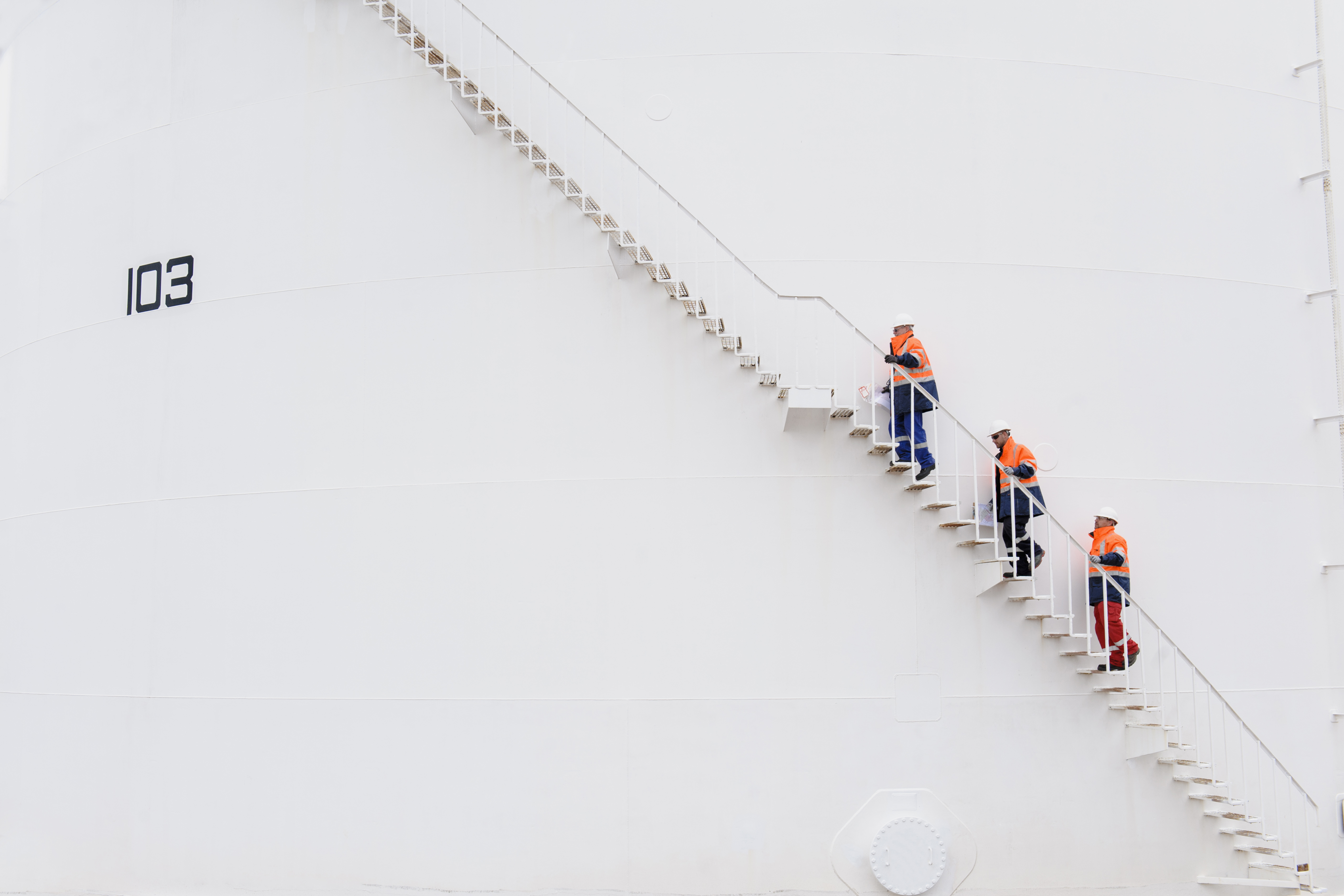 People in construction gear climbing up a ladder